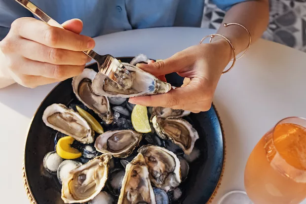 Woman eating oysters, which are among the best high iron foods